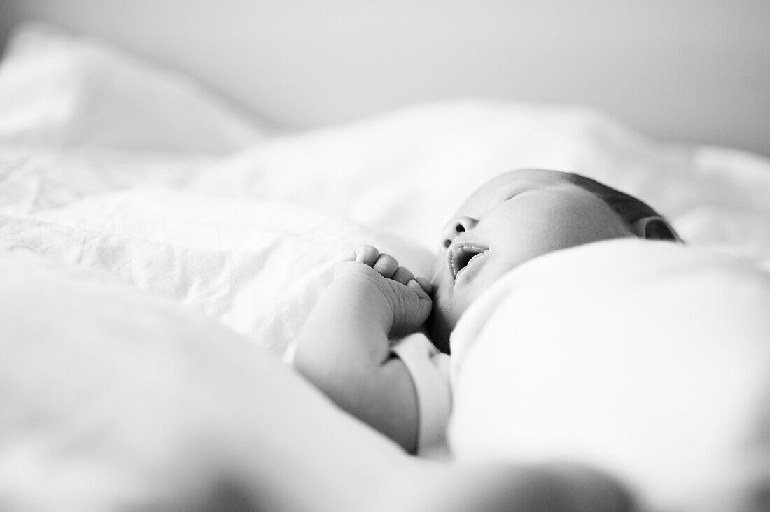 Newborn Baby in Onesie Sleeping on Bed