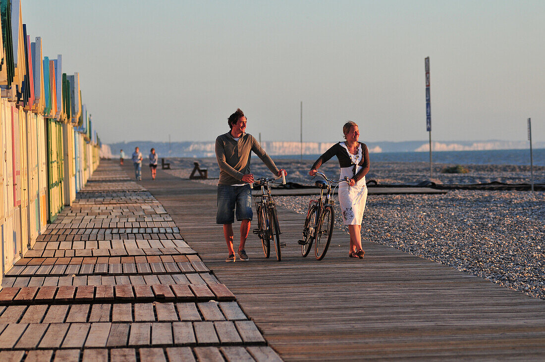 Couple Of Cyclists On The Beach Near Beach Huts At Sunset, Boardwalk Of Cayeux-Sur-Mer, Bay Of Somme, Somme (80), France