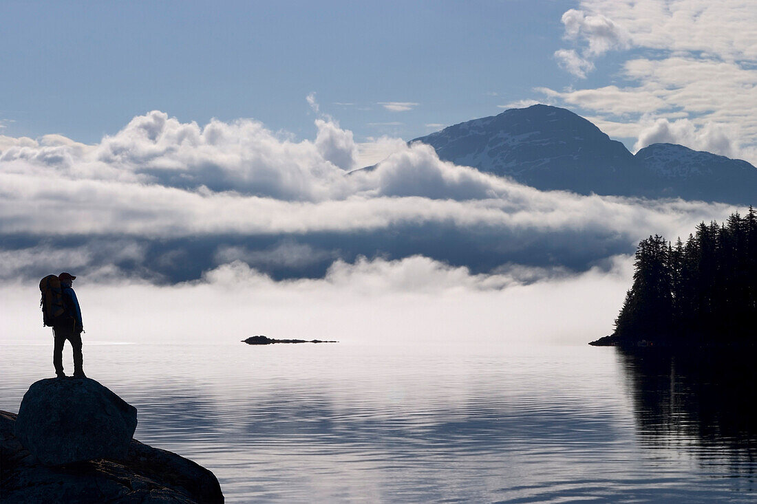 Composite: Silhouette Of A Backpacker Along The Shoreline Of Lynn Canal Near Juneau With Chilkat Mountains In The Background, Tongass National Forest, Inside Passage, Alaska