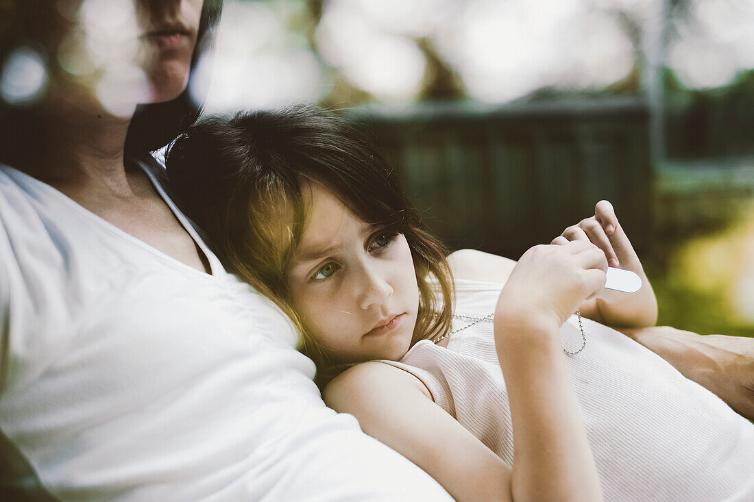 'Girl Cuddling Against Her Mother On A Chair In The Backyard;Otterburn Park Quebec Canada'