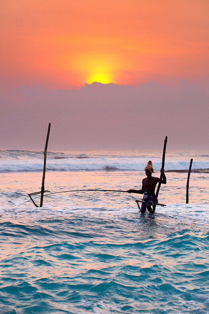 Sri Lanka - fisherman catches fish in a traditional way, Koggala Beach at sunset time, south part of Sri Lanka, Indian Ocean coast, Asia