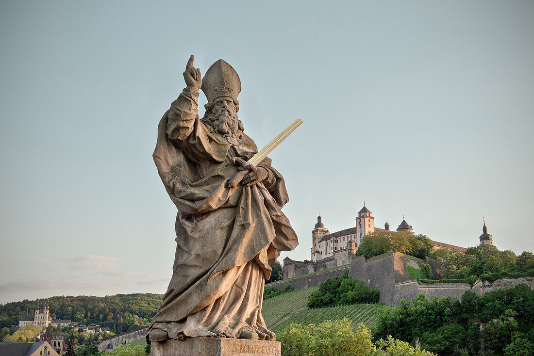 Heiligenstatue auf Alter Mainbrücke mit Blick auf Festung Marienberg, Würzburg, Franken, Deutschland