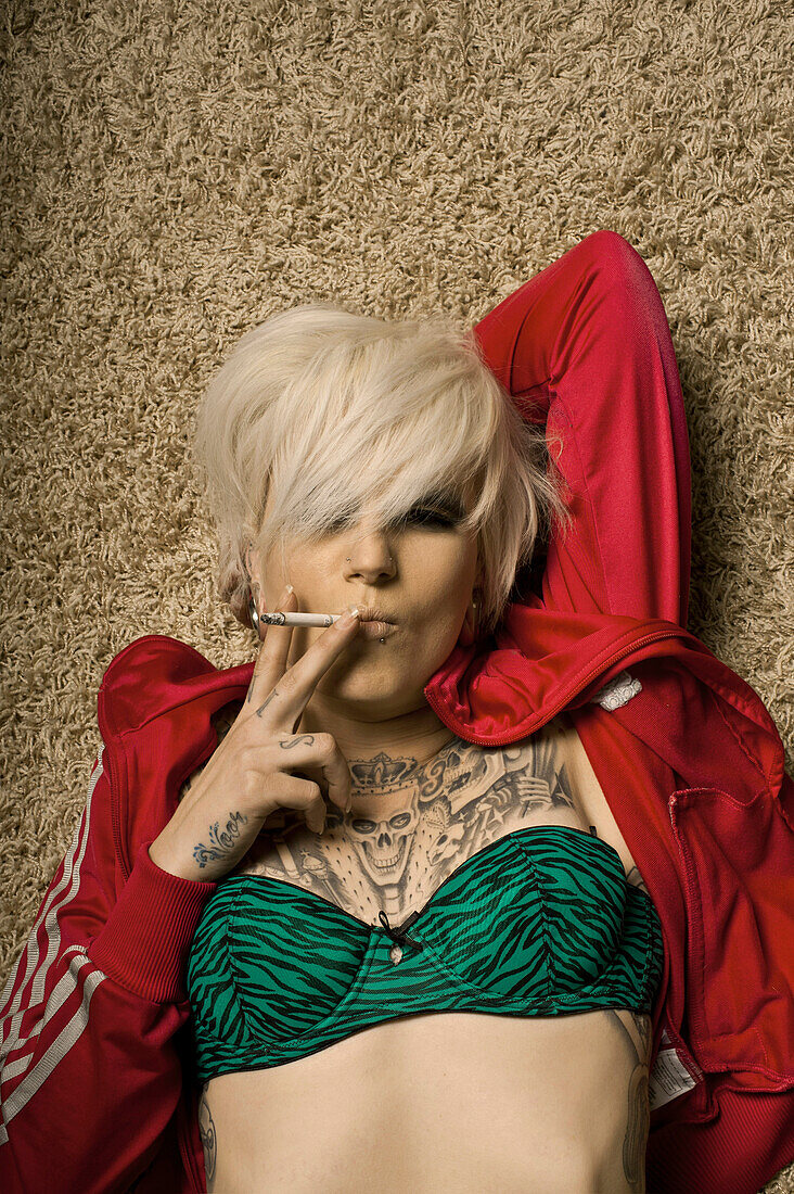 Blonde Women With Tattoos Lying On Carpet Smoking