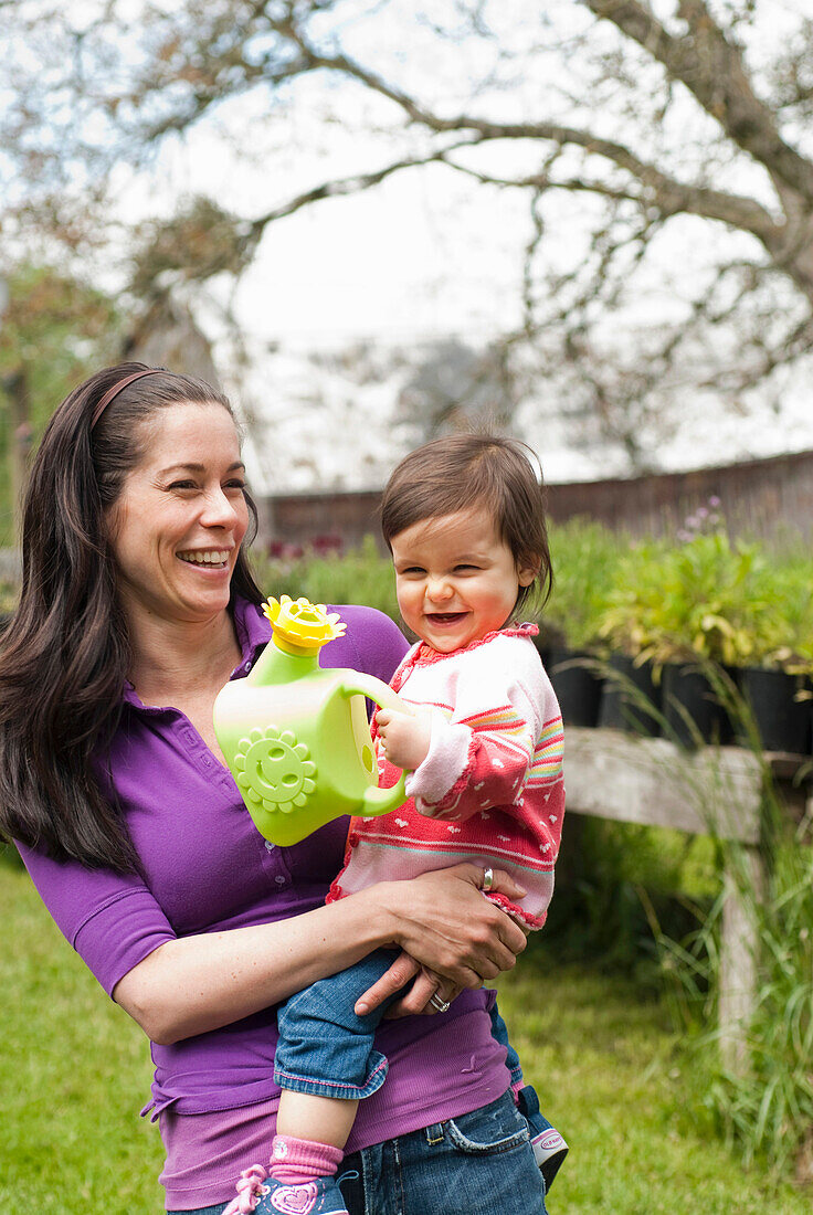 Mother And Daughter With Watering Can In Outside Garden, Vancouver British Columbia