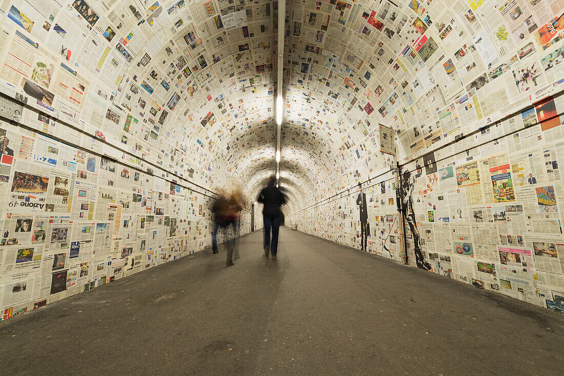 Pedestrians in a tunnel with walls covered in newspaper, Lugano, Ticino, Switzerland