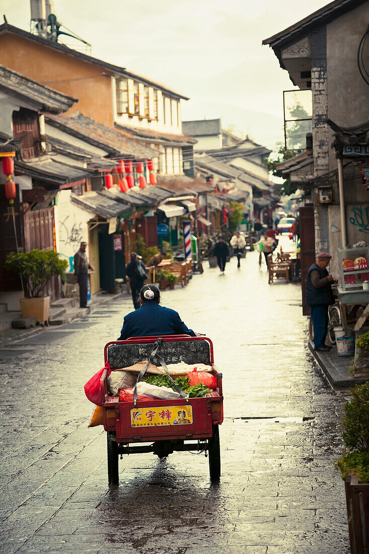 Woman rides tricycle with vegetables on Old City Dali streets, Dali City, Yunnan, China