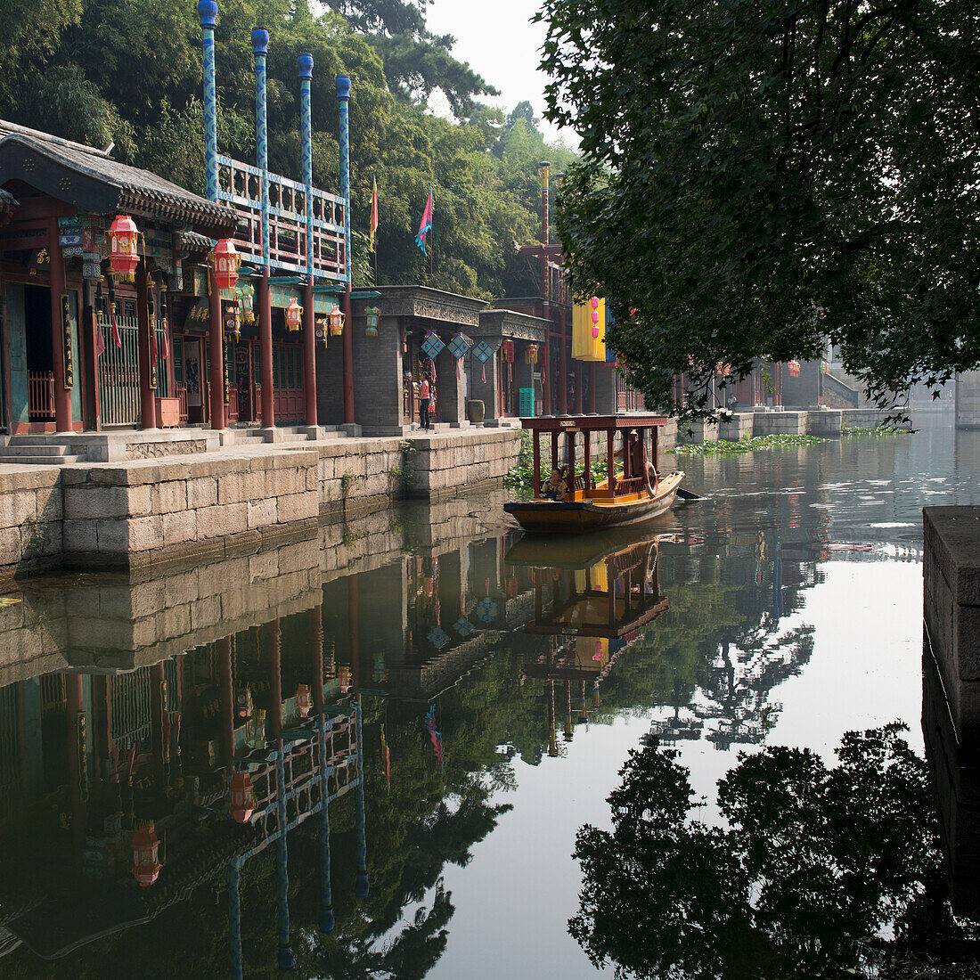 A boat in the tranquil river water and buildings along the water's edge, Beijing, China