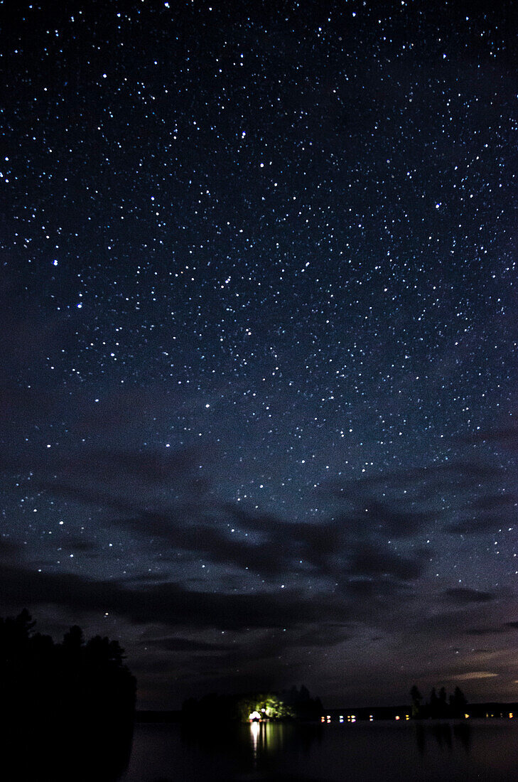 Stars in Cloudy Night Sky with Above Lake