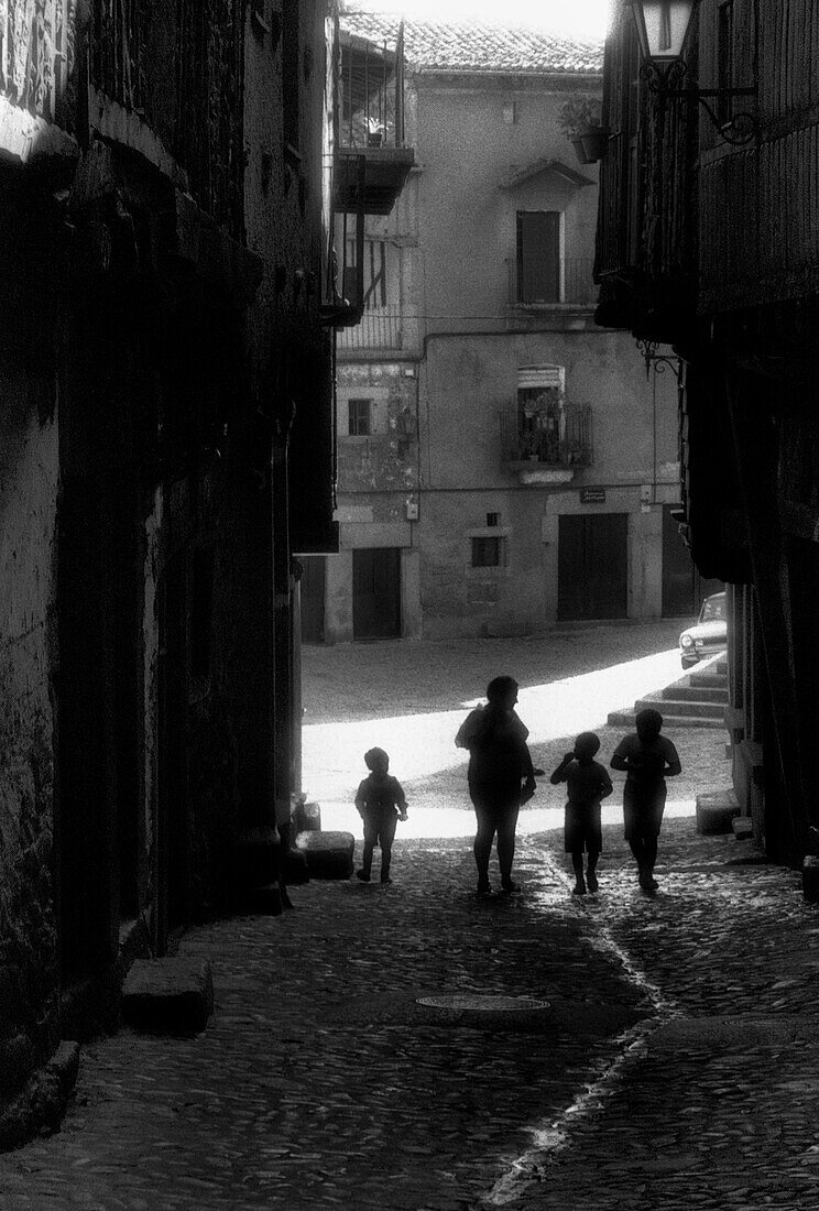 Woman and Children Walking Up Old Cobblestone Street, Silhouette, Spain