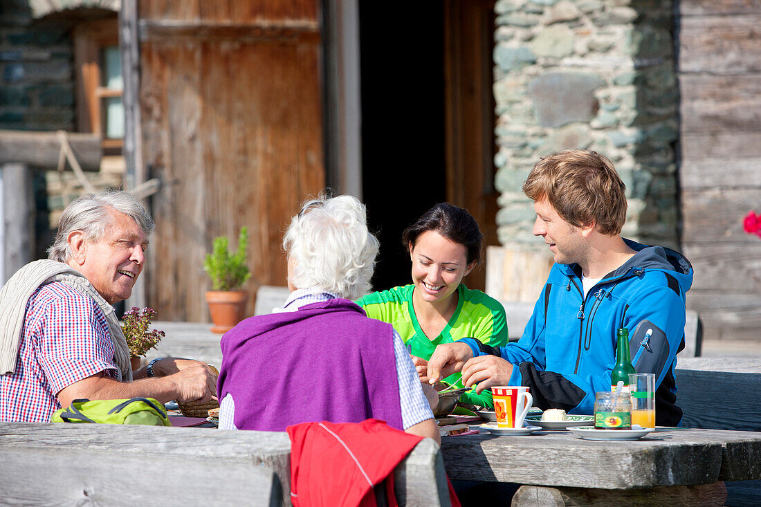 Four hikers having a snack in front of an alpine hut, Styria, Austria