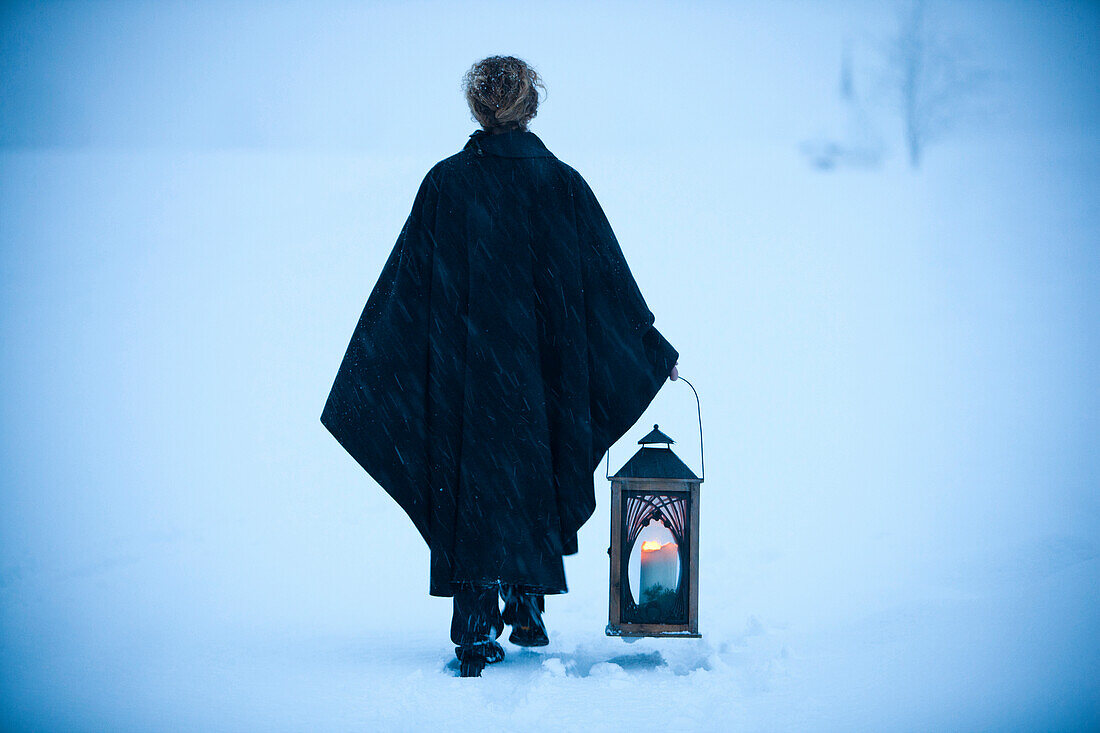 Woman carrying a lantern through snow, Styria, Austria