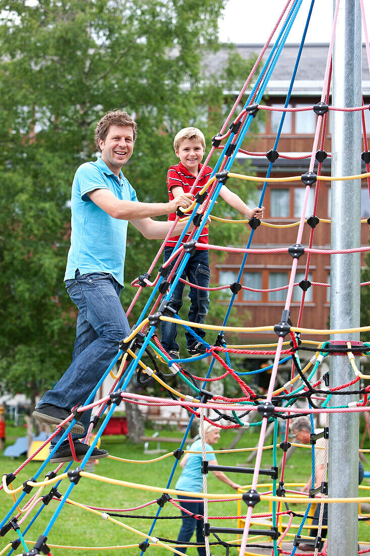 Father and son (7 years) on a climbing frame, Styria, Austria