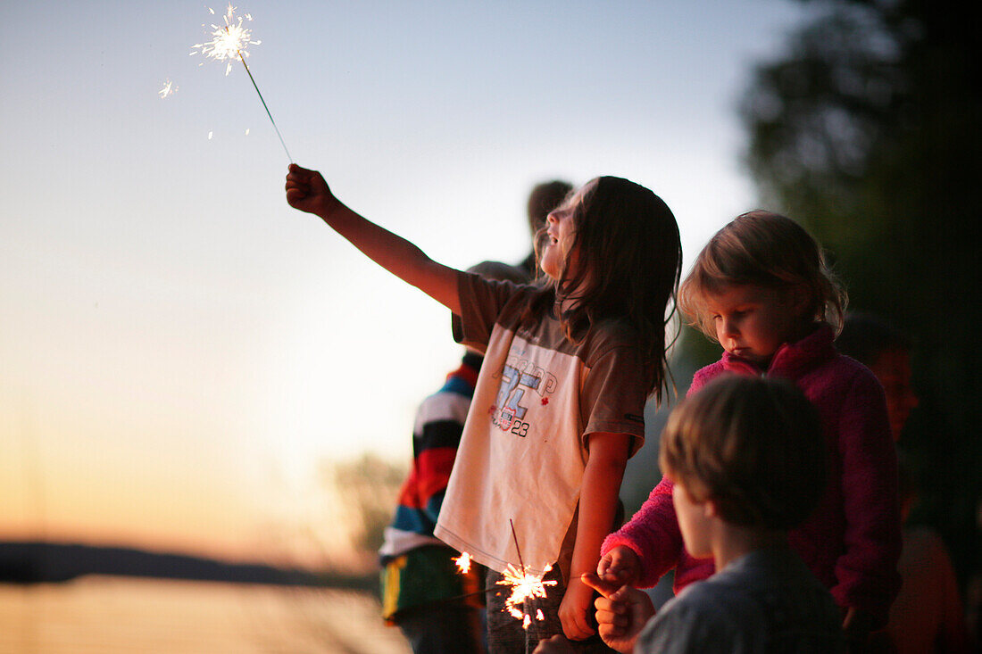 Children with sparklers at lake Starnberg, Ammerland, Munsing, Upper Bavaria, Germany