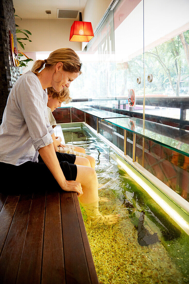 Woman and boy enjoying fish spa, Downtown Core, Singapore