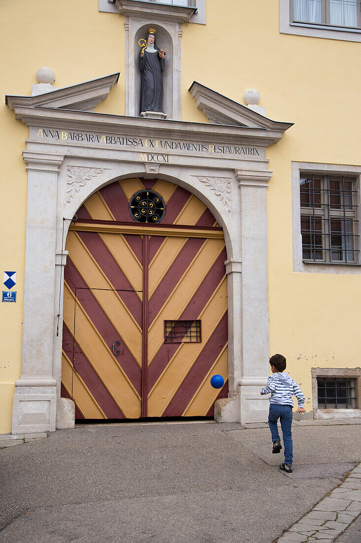 Boy kicking a ball against a door at St. Walburg abbey, Eichstaett, Altmuehltal, Franconia, Bavaria, Germany