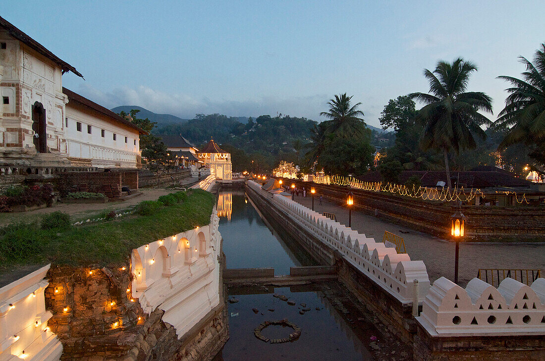 Wassergraben vor dem mit Lampen für die Perahera geschmückten Tempel des Heiligen Zahns Sri Dalada Maligawa, Kandy, Sri Lanka