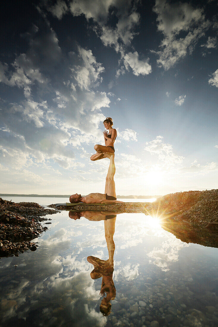 Couple practicing acroyoga at lake Starnberg, Upper Bavaria, Germany