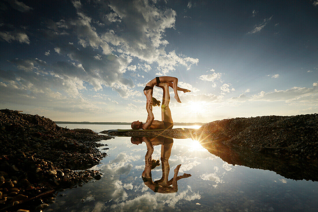 Couple practicing acroyoga at lake Starnberg, Upper Bavaria, Germany