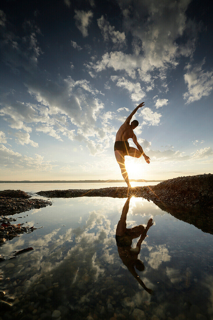 Man practicing acro yoga at lake Starnberg, Upper Bavaria, Germany