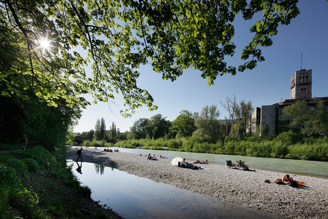 People sunbathing at river Isar, Deutsches Museum in background, Munich, Bavaria, Germany