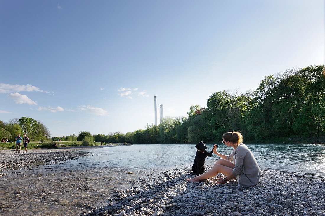 Woman playing with a dog at river Isar, Wittelsbach bridge, Munich, Bavaria, Germany