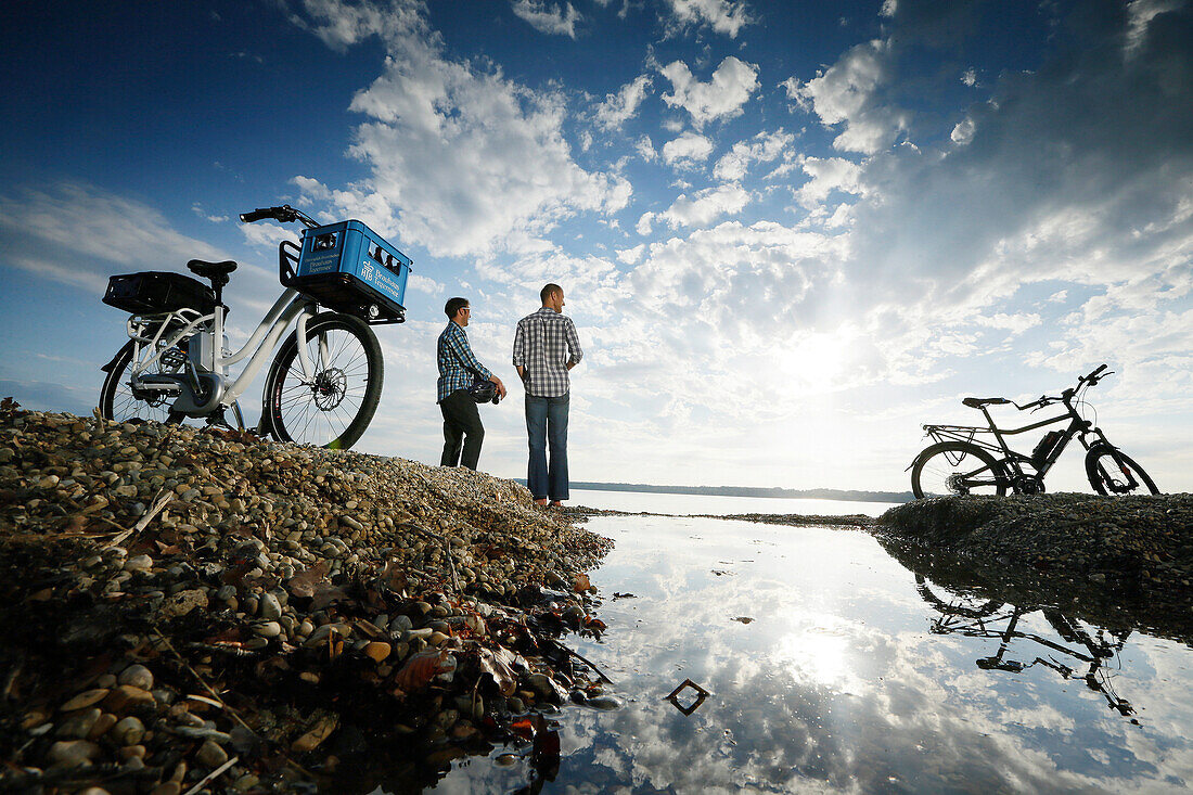 Two men with e-bikes resting at lake Starnberg, Upper Bavaria, Germany