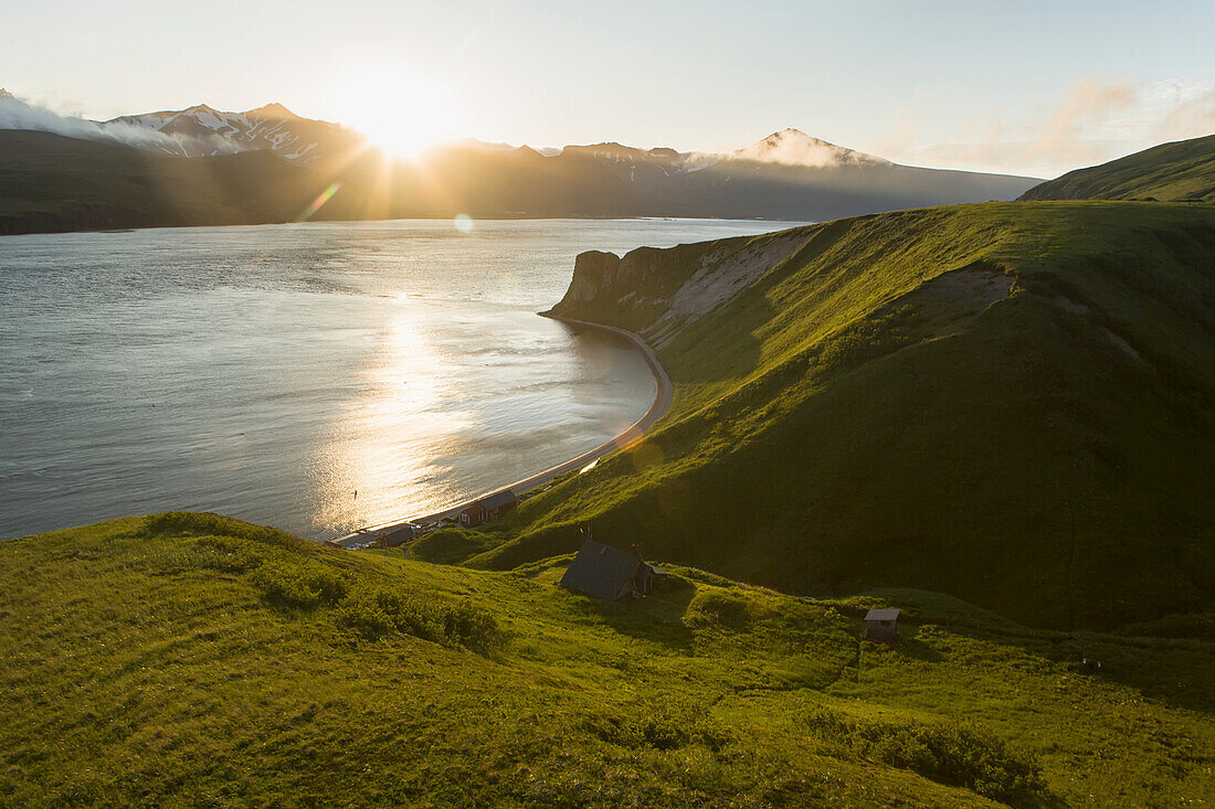 The sun setting behind Unimak Island from the bluff above the Laukitis fishcamp in False Pass, Southwest Alaska, summer.