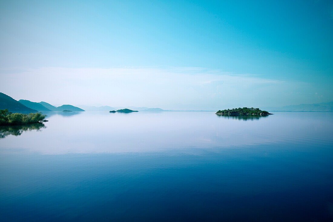 Smooth water surface with view of the surrounding mountains and tiny islands, Murici, Lake Skadar National Park, Montenegro, Western Balkan, Europe