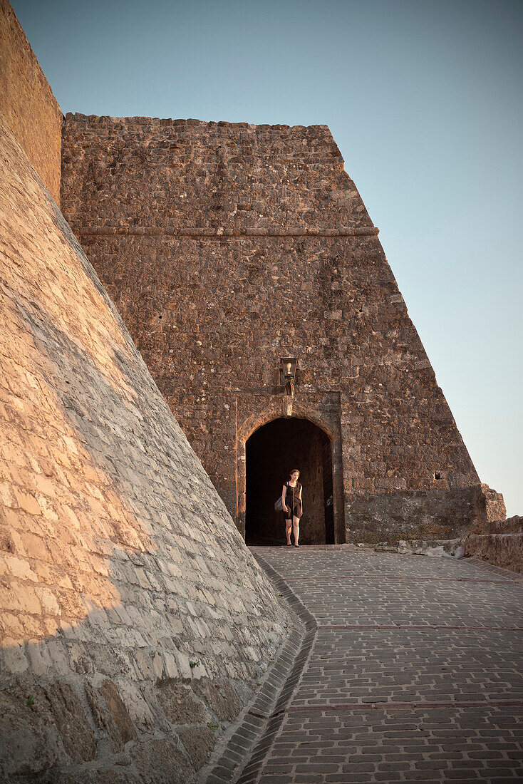 Young woman walking through a gate of the old town of Ulcinj, Stari Grad, Adriatic coastline, Montenegro, Western Balkan, Europe