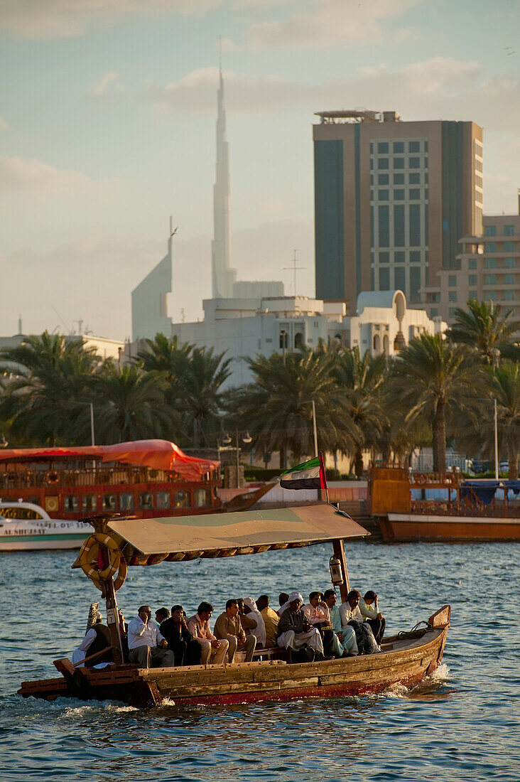 People on water taxi at dusk at the Creek with the Burj Kalifa, Dubai, UAE