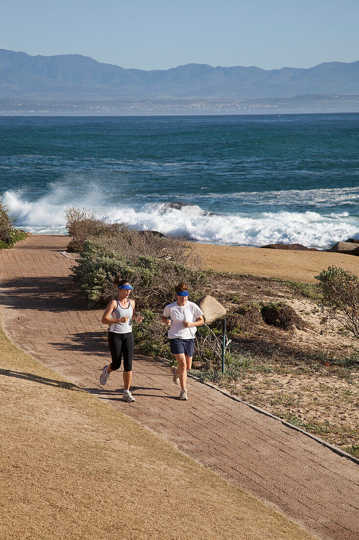 South Africa, Couple running along shore, Mossel Bay