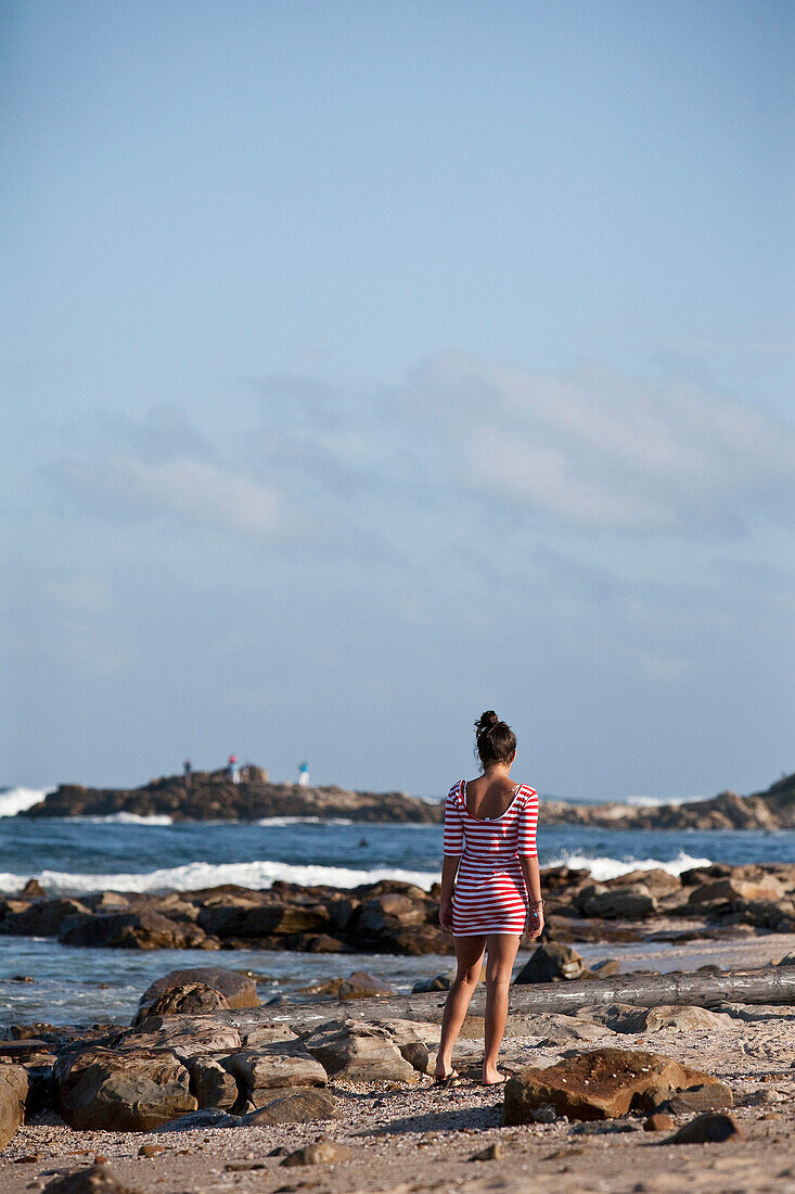 South Africa, Young woman walking along seashore, Mossel Bay