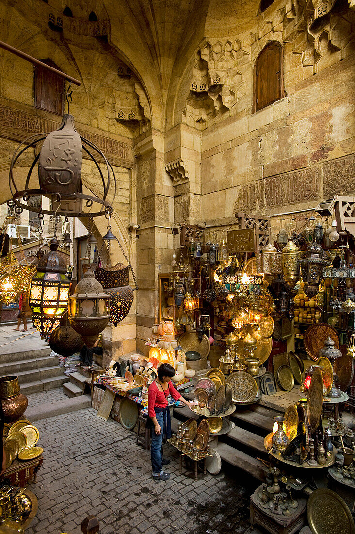 Woman shopping at stalls in covered gateway in Khan El Khalili, Cairo, Egypt