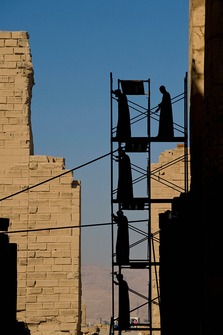 Silhouette of men putting up scaffolding on Karnak Temple, Precinct of Amun, Luxor, Egypt