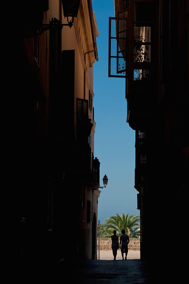 Couple walking along narrow alley, Palma, Majorca, Spain