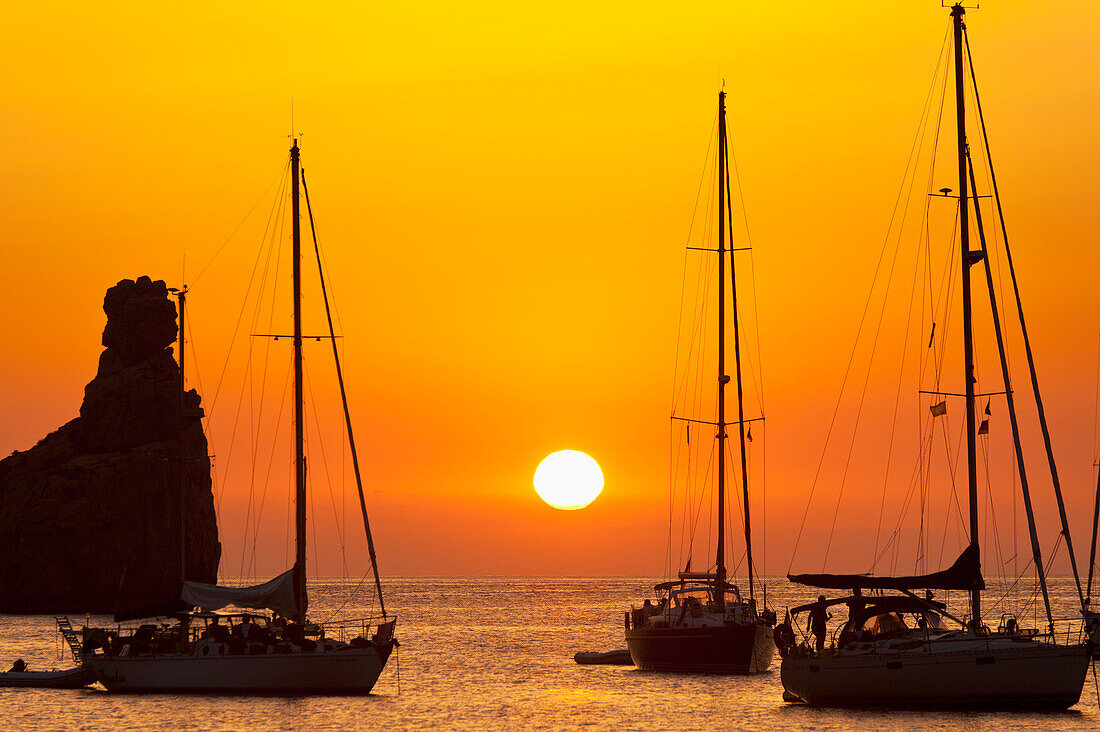 Yachts and strange shaped rock off Benirras Beach at dusk, Ibiza, Spain