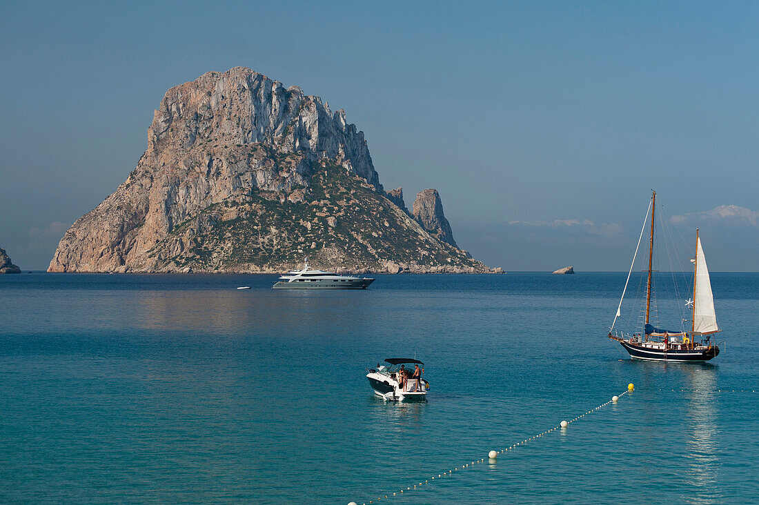 People on boats off Cala d'Hort beach with Es Vedra Island behind, Ibiza, Spain