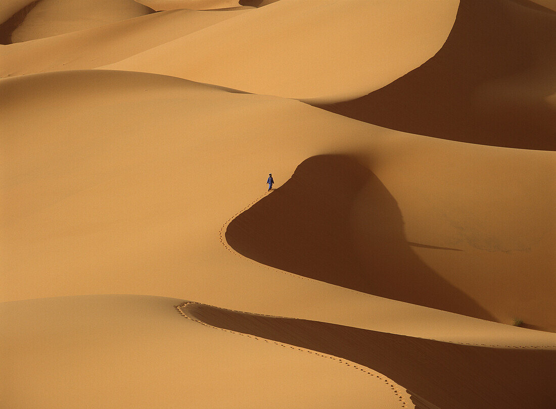Berber 'blue man' walking through sand dunes in Erg Chebbi near Merzouga, Sahara Desert, Morocco