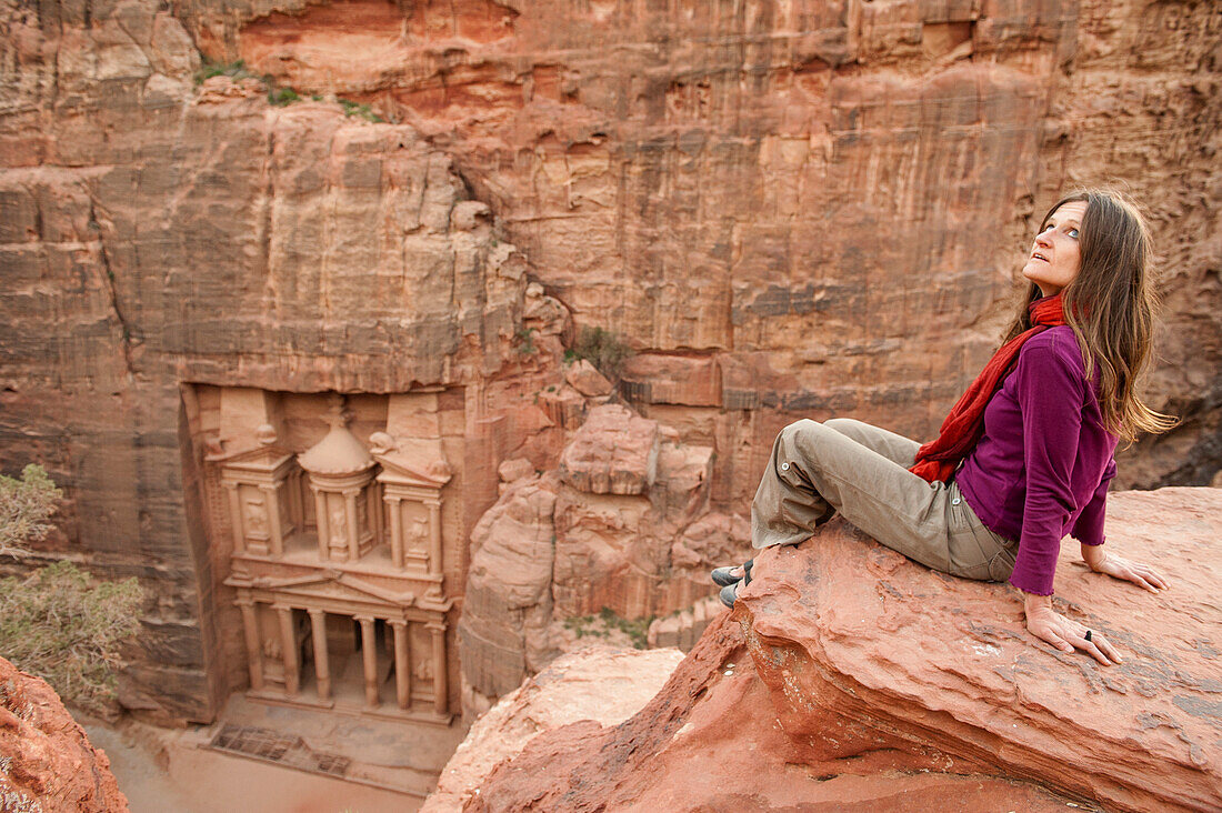 Woman sitting on a rock, Al Khazneh in background, Petra, Jordan, Middle East