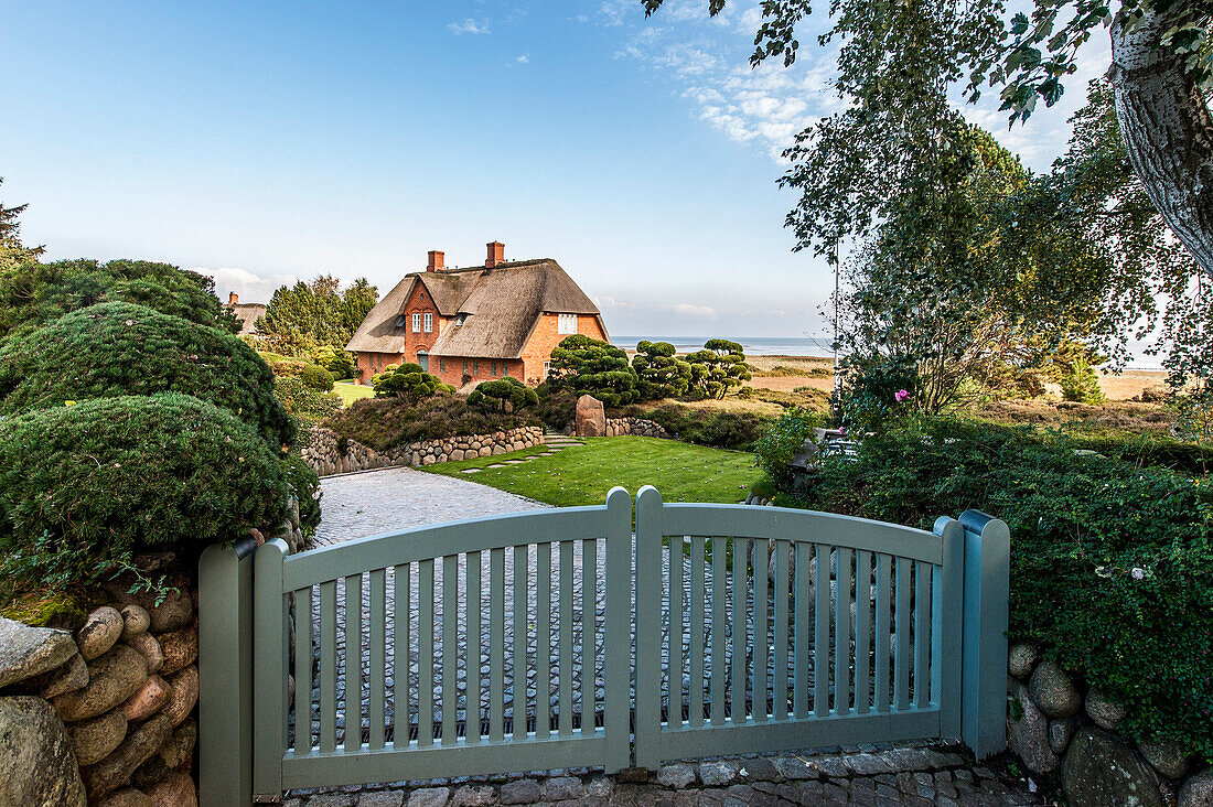 Thatched-roof house with Wadden Sea in background, Kampen, Sylt, Schleswig-Holstein, Germany