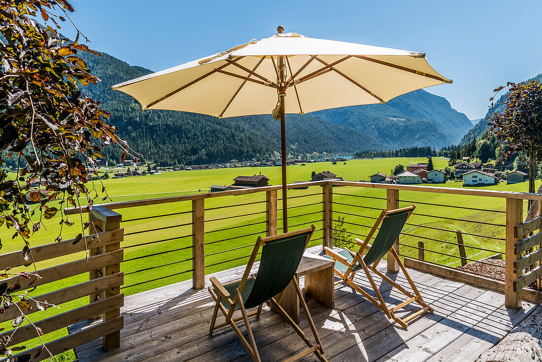 Deckchairs and sunshade on a terrace, lake Achensee and Achenkirch in background, Tyrol, Austria
