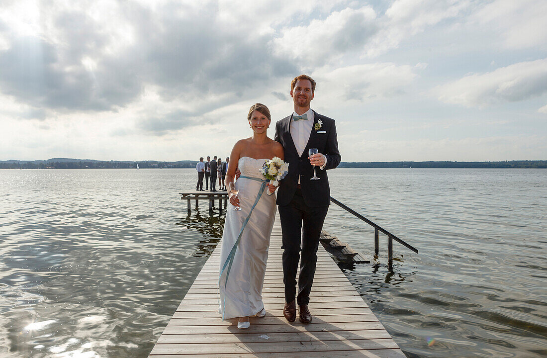 Brautpaa geht auf einem Steg entlang, Starnsberger See, Bayern, Deutschland