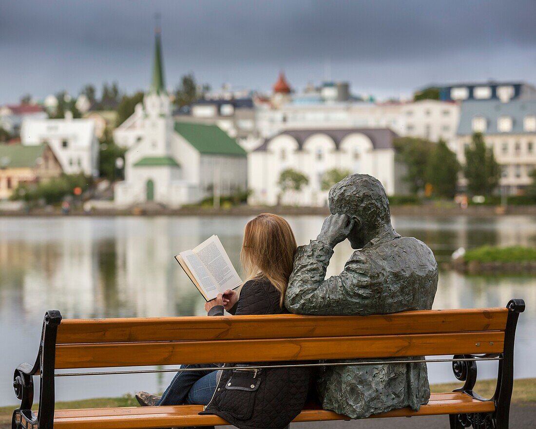 Woman reading next to statue of an Icelandic poet, Tomas Gudmundsson, Reykjavik, Iceland The city of Reykjavik has been designated as a UNESCO city of literature