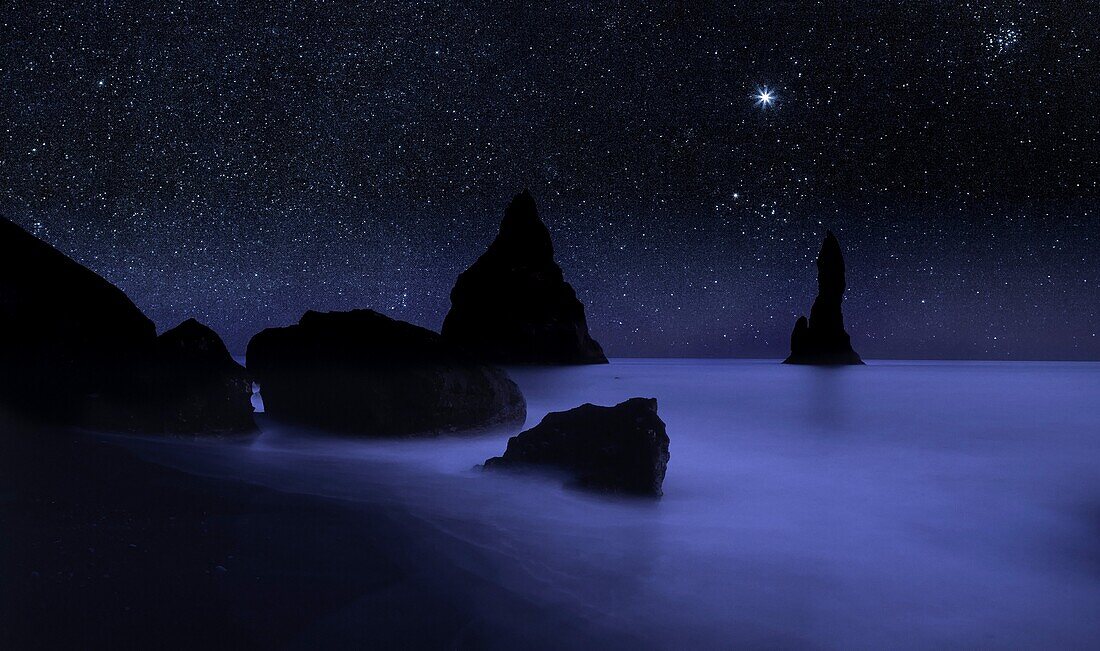 Starry night sky and Reynisdrangar cliffs, South Coast, Iceland digital composite