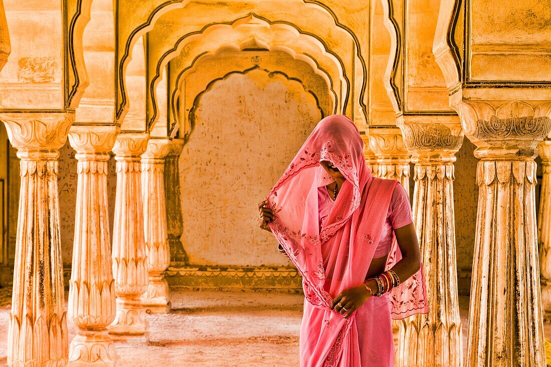 Beautiful graphic arches with colorful Hindu gentle woman posed at Amber Fort temple in Rajasthan Jaipur India