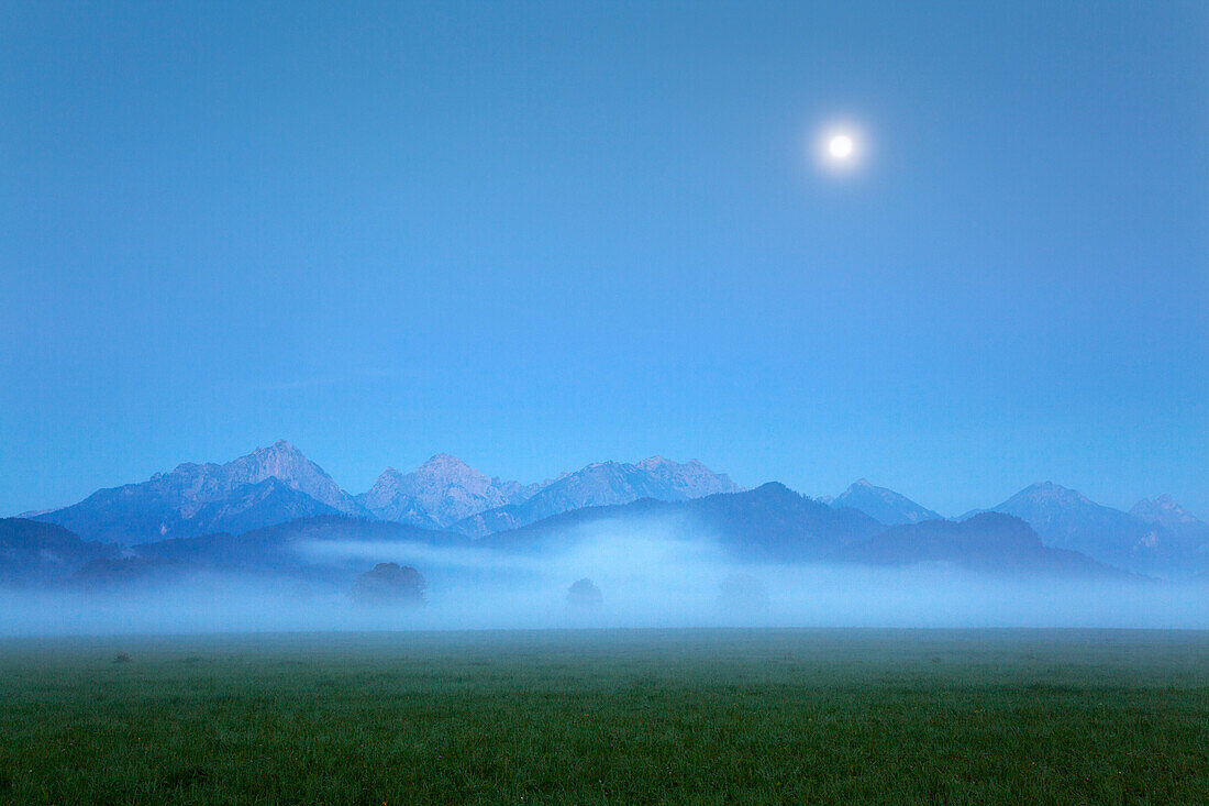 Tannheim mountains in the morning mist and moonlight, Hohenschwangau, near Fuessen, Allgaeu, Bavaria, Germany
