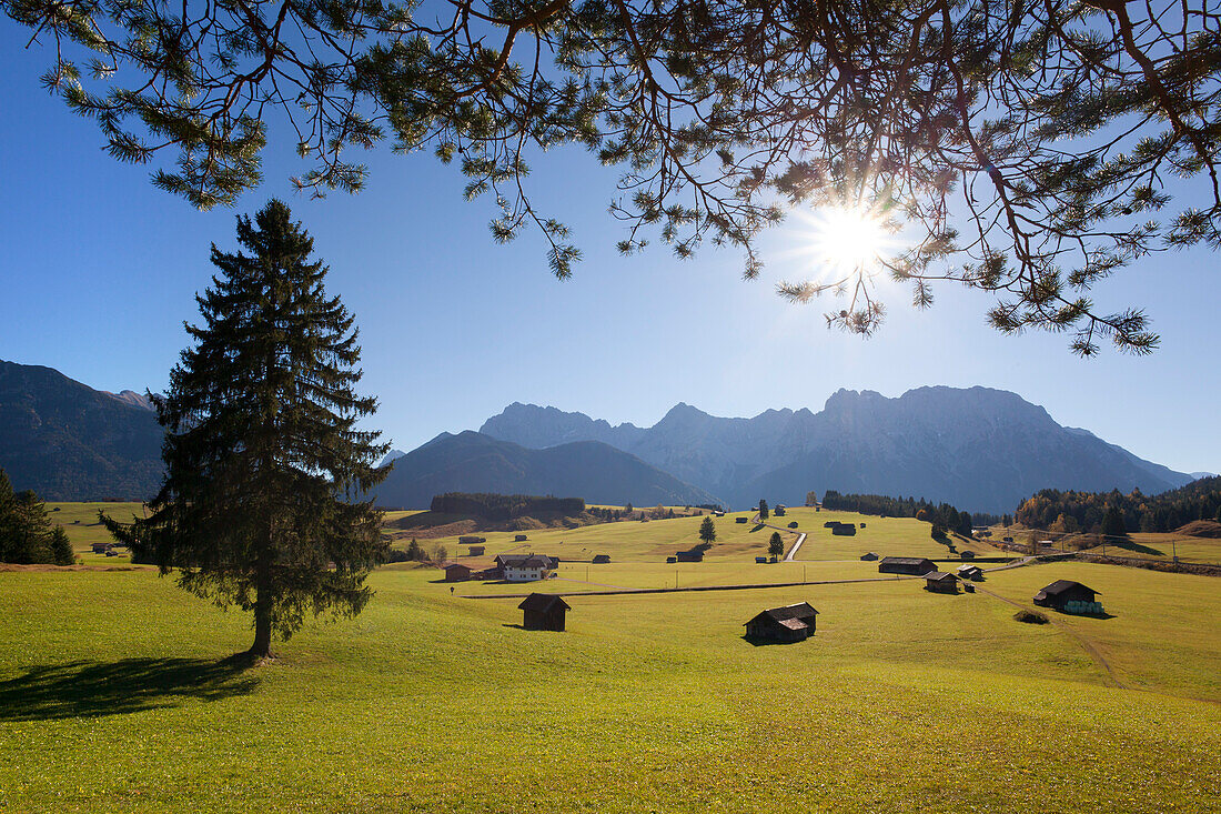 Almwiese mit Bauernhöfen und Heustadeln vor dem Karwendelgebirge, bei Mittenwald, Bayern, Deutschland