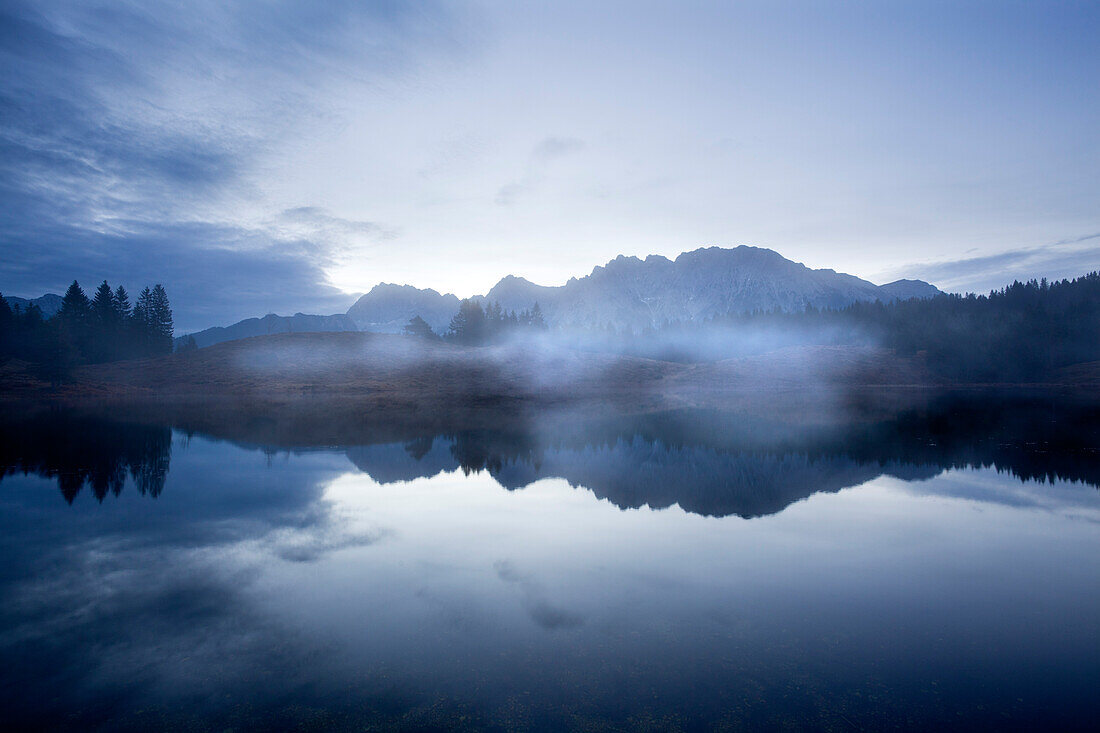 Morning mist, Karwendel mountains reflecting in lake Wildensee, near Mittenwald, Bavaria, Germany