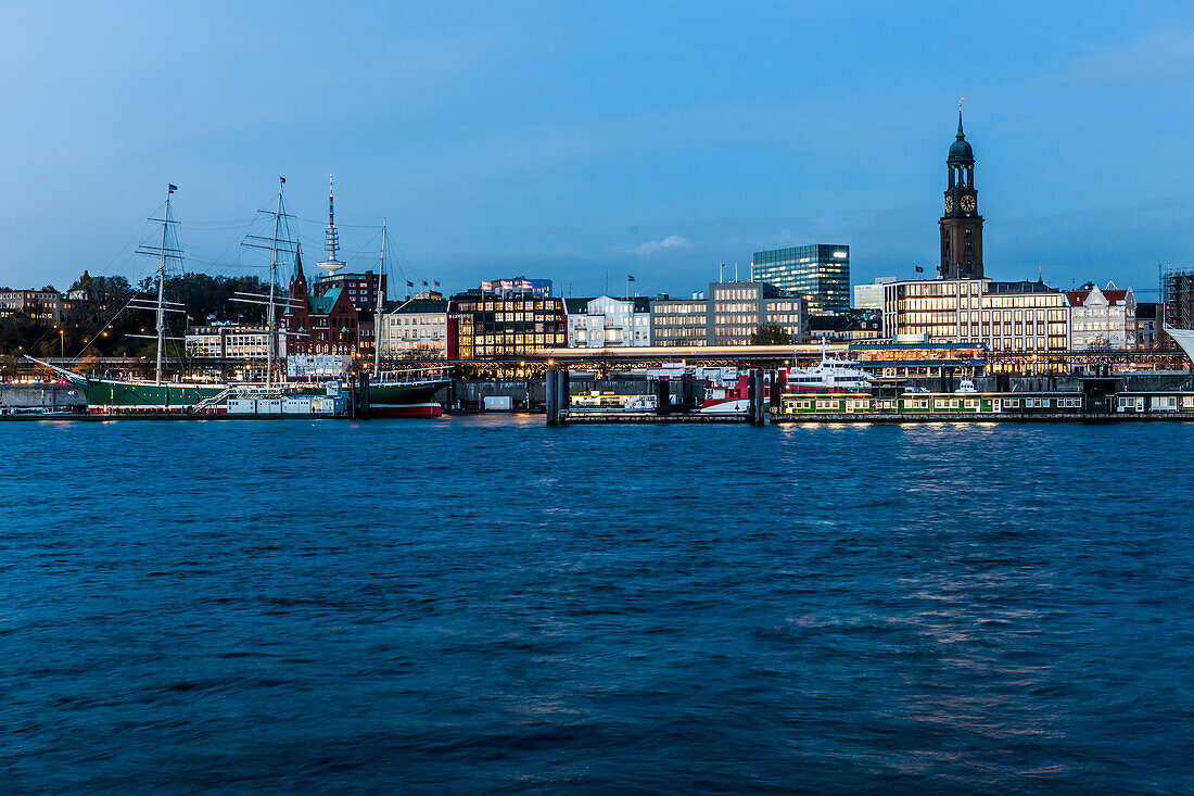 View ove river Elbe to Landungsbruecken and church St. Michael in the evening, Hamburg, Germany