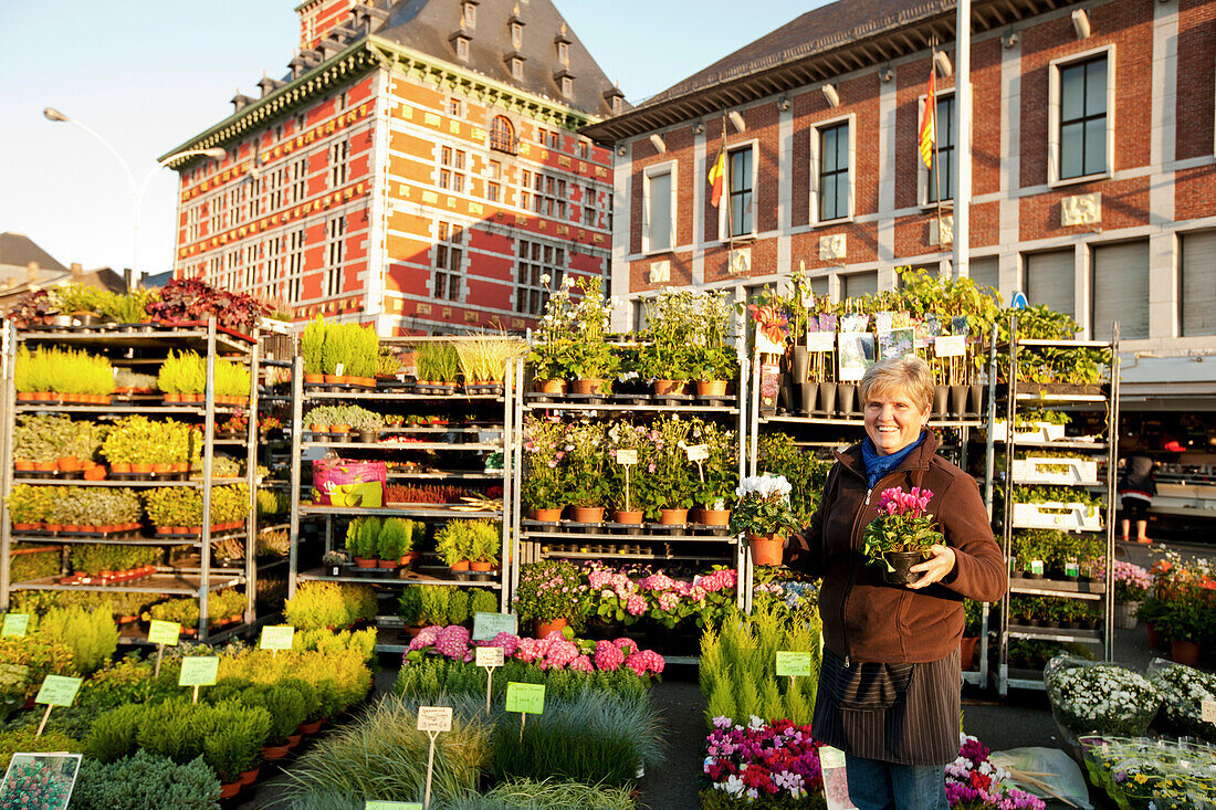Blumenverkäuferin auf dem Markt La Batte, Museum Grand Curtius im Hintergrund, Lüttich, Wallonien, Belgien